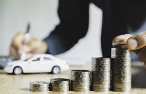 Pilhas de moedas na mesa enquanto um homem compra um carro