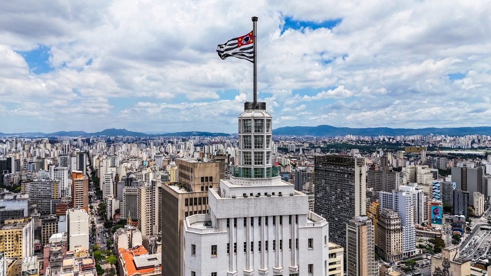 Vista aérea do centro de São Paulo com o Edifício Banespa (Altino Arantes) em destaque e a bandeira do Estado de São Paulo no topo.
